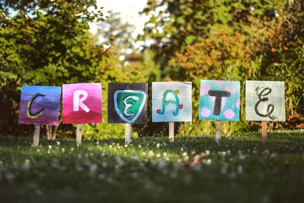 painted signs with the word create in a grassy field.